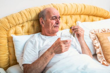 Bunalımlı son sınıf öğrencisi sabahları yatakta yatarken hap içiyor..