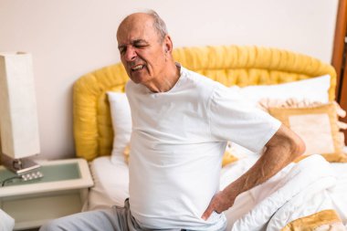 Kıdemli adam sabah yatağında otururken sırtı ağrıyordu..