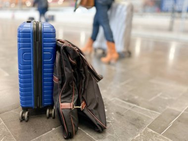 Blue suitcase and garment rack on the platform floor of a modern long-distance train station