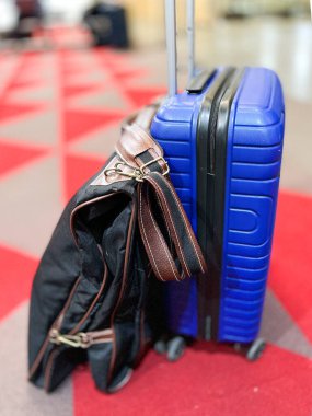 Blue suitcase and garment rack on the platform floor of a modern long-distance train station
