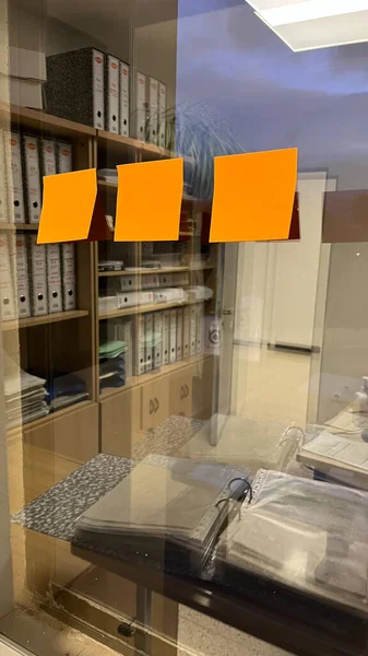Orange sticky reminder notes on glass in office