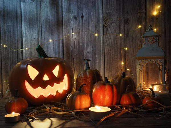 Halloween pumpkin head lantern with candles an pumpkin on wooden background