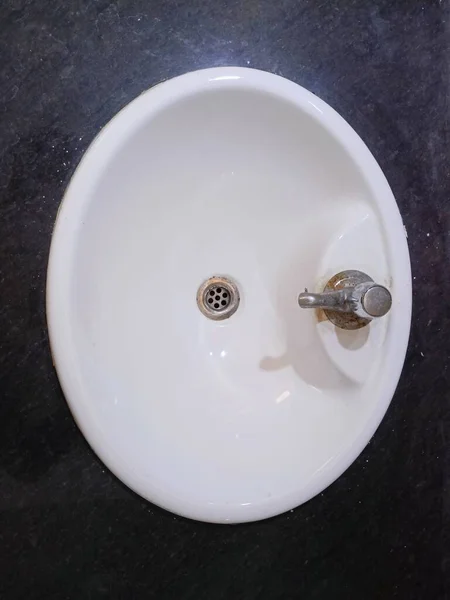 wash basin with steel tap. white colour basin  with middle a hole.