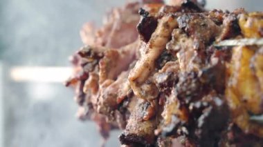 Ev yapımı terbiye edilmiş ve baharatlı et filetosu yavaş yavaş yanan ateşin üzerindeki çelik tükürüğün üzerinde dönüyor. Piknik partisi için barbekü dumanında kızartılmış et parçaları. Et mangalı, kızartma.