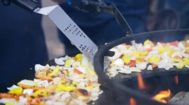 Geleneksel sokak yemekleri, ızgara ızgara ızgara ve yakacak odun, eldivenli adam ateşte yemeği karıştırmak için çelik spatula kullanıyor. Sağlıksız veya abur cubur konsepti. Yüksek
