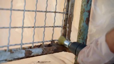 İnşaat alanında zor onarım işleri, eski paslı metal yüzeyi çelik fırçayla öğüten eldivenler, doğal koşullardan kaynaklanan ağır metal nesne aşınması. Metal