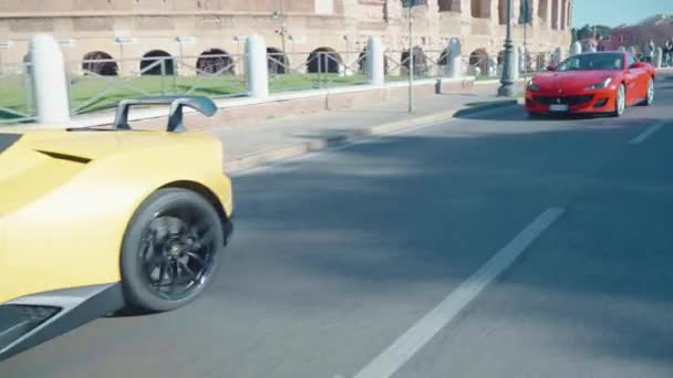 ローマ イタリア 2022年11月7日 ローマの有名なコロッセオ通りに沿って強力な黄色のランボルギーニと赤のフェラーリの運転 エリートプレミアムクラスのスポーツカーの性能 高級レーシングカー — ストック動画