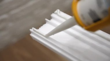 Beyaz süpürgelik yüzeyine beyaz yapıştırıcı sürme işlemi, evde nesneleri tamir etmek için tutkal tübü kullanarak daire plinth kurulumu için yapışkan yapıştırıcı. Yüksek kalite 4k