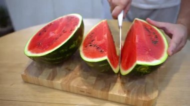 Çizgili sulu karpuzu mutfak bıçağıyla doğrayan adam, olgun böğürtlen, siyah tohumlarla ve tatlı sulu hamurla ahşap kesme tahtasıyla, taze mevsimlik meyveleri yiyen yardımcı vitaminlerle dolu.