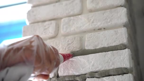 建設現場での作業プロセス 工業用シリンジからのモルタルの圧迫と壁の接合部のギャップを埋める作業員 新鮮なセメントで壁の縫い目の溝 家庭の壁の改修と改善 — ストック動画