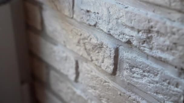 建設現場の壁に白い装飾石 柔らかい工業用ブラシを使用して白い色の塗料と手袋塗装石のタイルの労働者 改修インテリア作品 家の改善コンセプト — ストック動画