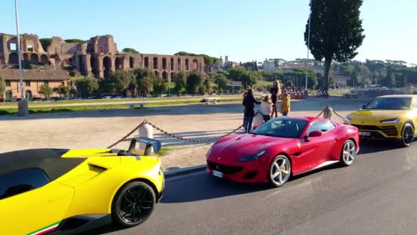 ローマ イタリア 11月7 2022 駐車高級スポーツカー 排他的な赤フェラーリとローマ中心部の通りの側道に2つの黄色のランボルギーニ車の近くにFori Imperaliの友人のグループ — ストック動画