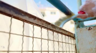 Metal kapı yüzeyini elle tarayan işçiler eski soluk boya ve pası kaldırarak doğal koşullar altında oluşan korozyonu ortadan kaldırıyor. Çeliğin ağır aşınması