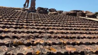 UMBRIA, ITALY - JUNE 18, 2022: Construction builders renovating rooftop of ancient house on the suburbs of Umbria region in Italy, weathered destructed roof of an old house in the countryside, men