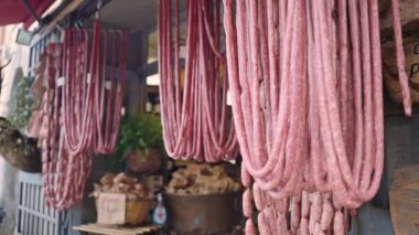 Hanging meat delicatessen in traditional Italian local store, dried and smoked meat products of high quality for selling, assortment of rustic food in butchery store, appetizing food industry concept