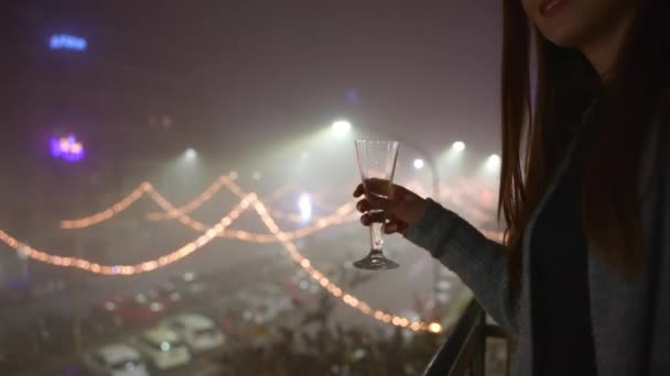 照らされた通りのお祝いの背景に対してかなりの女性の手の中に輝くシャンパンや白ワインのクリスタルガラス バルコニーでアルコールを飲むと夜のパーティー エンターテイメントのコンセプト — ストック動画