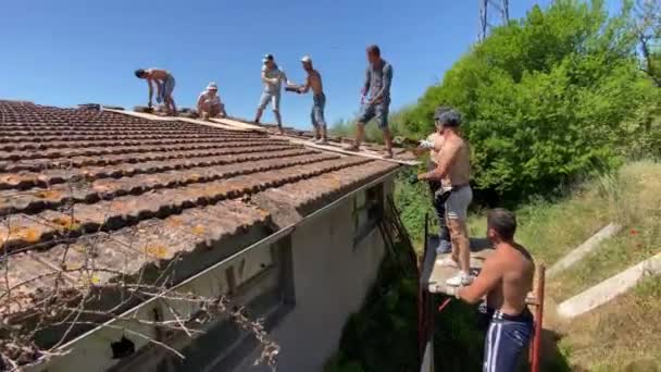Umbria イタリア 2022年6月18日 放棄された家の屋根の表面を取り壊すチーム労働者は 古い赤い粘土瓦を取り除き 作業服の修理人とウンブリアで働く手袋を保護する — ストック動画