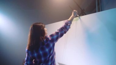 Talented female artist creating abstract masterpiece on canvas with oil painting, woman drawing colourful horizontal line embodying her imagination in artwork. Contemporary fine art, innovative oil