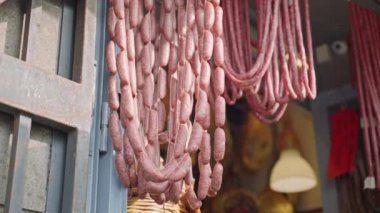 Traditional Italian local store with assortment of smoked and dried meat products, delicious food on butchers store counter, hanging appetizing sausages and salami for selling, Italian delicatessen