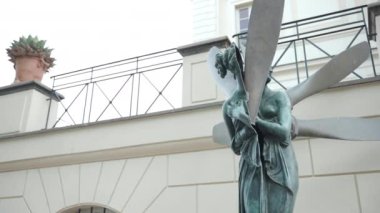 Historic metal statue on the background of white villa palace decorated with terrace, arch shaped windows and greenery. Majestic reconstructed exterior facade of historic villa residence, antique