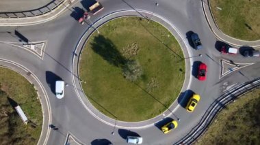 Green urban roundabout with road junctions of different directions from aerial view, exclusive sports car driving in roundabout in traffic time, performance of extreme sports cars on urban streets