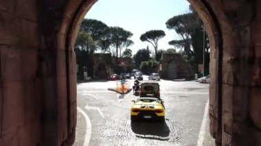 ROME, ITALY - NOVEMBER 7, 2022: Exclusive sports cars performance on the streets of Rome, supercars driving on cobblestone passing ancient stone historical arch, sports cars racing performance. High