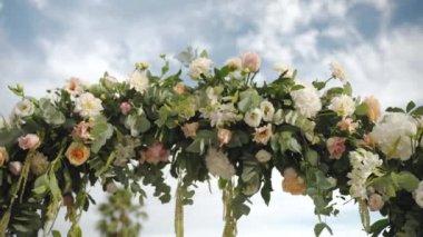 Round arch of fresh flowers on wedding ceremony, aristocratic flowers arch on cloudy sky background, arrangement and decor details for ceremony on royal Villa terrace, exclusive wedding style concept