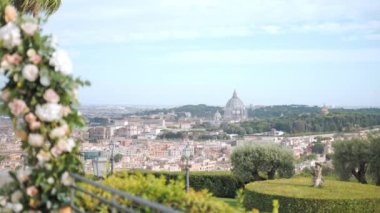 Amazing panoramic view of architectural Vatican Dome through the round fresh flowers arch on ancient Villa terrace, Vatican city as an European religious centre for tourists from all over the world