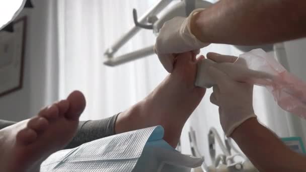 在医疗中心进行扁足强化治疗 手套专家将病人的脚放在医疗室内进行治疗 用于治疗疾病 矫形外科和其他方面的专用设备 — 图库视频影像
