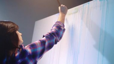 Studio artwork under the dim illumination, female painter creating abstract picture on canvas with acrylic colours and paintbrush, inspired artist embodying her imagination on canvas, contemporary