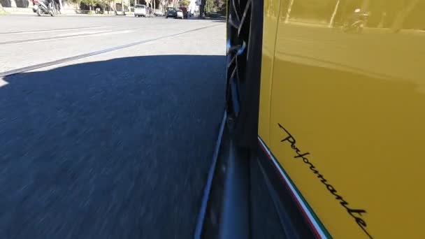 ローマ イタリア 2022年11月7日 トラムの線路 横断歩道 その他の道路標識を通過する古代ローマの通りを横断する排他的な黄色のランボルギーニの運転 ランボルギーニホイールの回転 — ストック動画