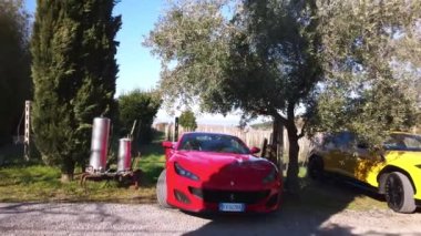 ROME, ITALY - NOVEMBER 7, 2022: Exclusive sports cars with convertible roof parked in Italian countryside, red Ferrari and yellow Lamborghini in the vineyard, powerful premium class cars on grand tour