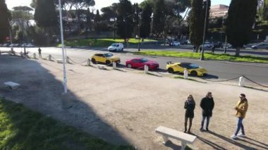 ROME, ITALY - NOVEMBER 7, 2022: Group of friends against parked sports cars background on Roman Fori Imperiali, exclusive Ferrari and Lamborghini of exquisite collection, premium class cars in Rome