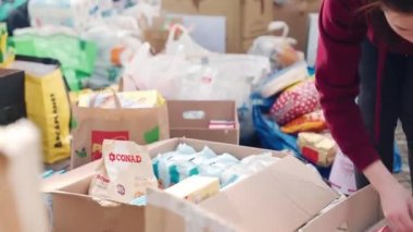 ROME, ITALY - MARCH 10, 2022: Cartoon boxes with basic necessities for Ukrainian refugees during the war, volunteers in Rome sorting humanitarian aid before loading on truck, lots of food for victims