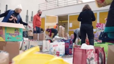 ROME, ITALY - MARCH 10, 2022: Cartoon boxes and packages with food, medicine, clothes, things for children and domestic animals, and other necessary things gathered for Ukrainian refugees during the