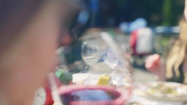 Friends dinning in rustic restaurant under the open air, shoulder shot of pretty woman drinking tasty red aged wine from crystal glass, high quality red wine in goblet, elegant lunch concept. High