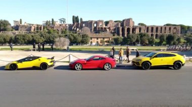 ROME, ITALY - NOVEMBER 7, 2022: Exclusive Ferrari and Lamborghini automobile of unique design parked in the city centre of Rome, elite cars collection against Fori Imperiali background, luxury cars