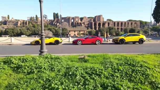 意大利罗马 2022年11月7日 针对古罗马废墟全景的独家超级汽车展览 一群富有的朋友在停放在街上的跑车旁欣赏壮观的建筑风景 — 图库视频影像