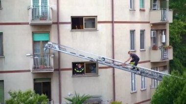 ROME, ITALY - AUGUST 27, 2021: Emergency rescue operation in residential building in the downtown of Rome, firefighters in working uniform and face mask lifting on rescue crane to persons balcony to