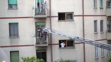 ROME, ITALY - AUGUST 27, 2021: Team of firefighters lifted on crane ladder on balcony and opened the windows to apartment to save persons life being abandoned after death for a long time, emergency