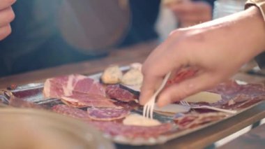 Traditional Italian aperitif in local restaurant of traditional cuisine, people tasting slices of high quality prosciutto di parma, salami, parmigiano cheese and typical gorgonzola, rustic snacks and