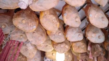 Lots of cured jamon legs and dried sausages hanging on ceiling in local grocery store, delicious Italian food delicatessen of rustic production, Italian seasonal prosciutto of high quality, Italian