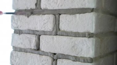 Dekoratif taş duvardaki eklemleri gruplandıran insanlar, özel endüstriyel harç spatulasıyla çimento döşeyen işçiler, dekoratif taş kiremitlerin montajı ve yüzey dokusunun restorasyonu