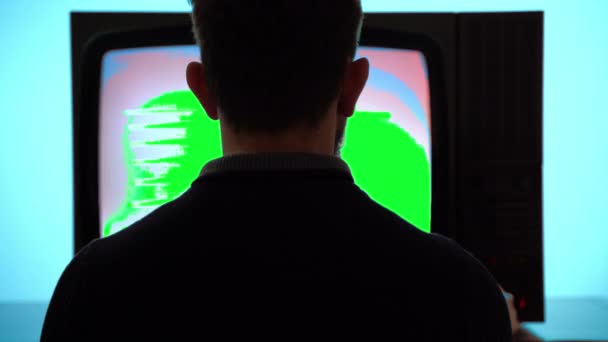 男人坐在复古电视前 绿色屏幕闪烁监视器和水平条纹 人们在控制面板上变换频道寻找好的电视信号 绿松石复古电视 — 图库视频影像