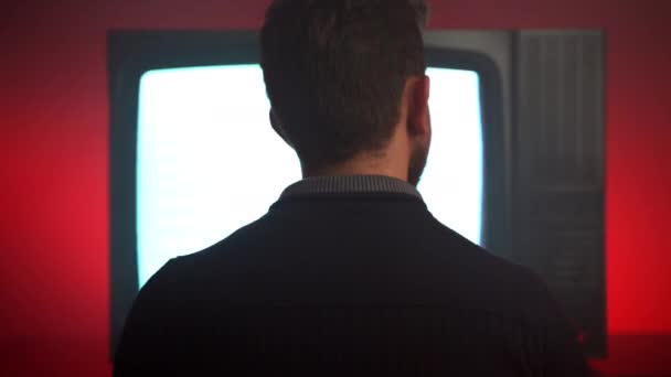 Kırmızı Arkaplan Karşısında Retro Televizyonun Önünde Oturan Adam Büyük Ilgi — Stok video