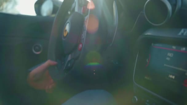 ローマ イタリア 2022年11月7日 太陽のフレアで排他的なスポーツカー内のドライバ 豪華なフェラーリクーペ車の男ステアリングホイール 高価なフェラーリPortofinoスポーツ車のエリートインテリアデザイン 動画クリップ