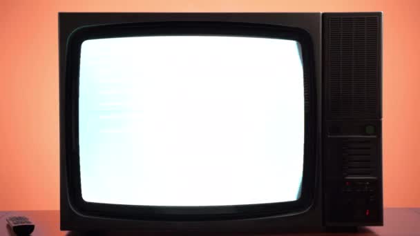 オレンジの背景に壊れたヴィンテージテレビで放送やニュースの伝送 点滅縞と悪い衛星信号のための画面歪みを持つレトロなテレビ ストック映像