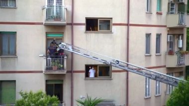 ROME, ITALY - 27 AĞUSTOS 2021: itfaiyeciler itfaiye merdiveni tırmanıyor konut binasının balkonuna girmek ve kapıları açmak için, Roma kurtarma operasyonu, itfaiyeciler hayat kurtarıyor