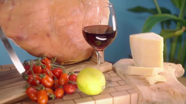 木製のスタンドの上にロイヤルジャモンの足は青を背景に 硬化ハムカットスライスは パルメザンチーズ レモン 赤ワインとトマトのガラスの近くのまな板に落ちます 伝統的な治癒 ストック映像