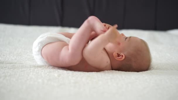 Bebê Menina Deitado Branco Folha Segurando Sua Legst — Vídeo de Stock